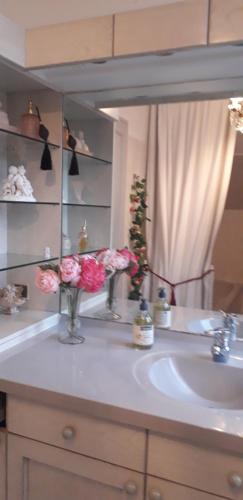 un lavandino in bagno con fiori in uno specchio di Côté jardin a Périgueux