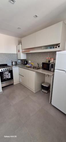 a kitchen with white cabinets and a white refrigerator at Amanecerpuertomadryn 4 in Puerto Madryn