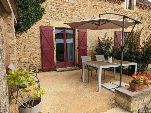 une table avec un parasol devant un bâtiment dans l'établissement Domaine de Fleurie, à Tursac