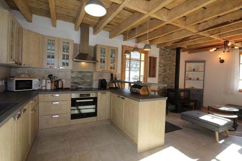 a large kitchen with wooden cabinets and a dining room at Chalet classé 5 étoiles avec bain nordique entièrement neuf in Luz-Saint-Sauveur