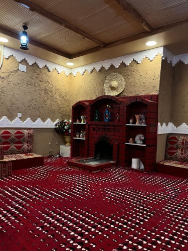 a large room with a fireplace and a red carpet at استراحة الورود in Tanomah
