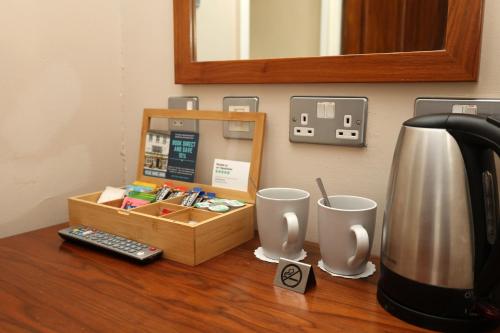 a counter with a coffee pot and two cups on it at The Olde Kings Arms in Hemel Hempstead