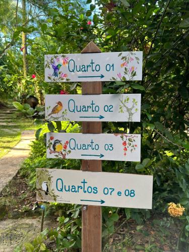 un cartel en un jardín con varias señales en Pousada Horizonte Azul, en Isla de Boipeba