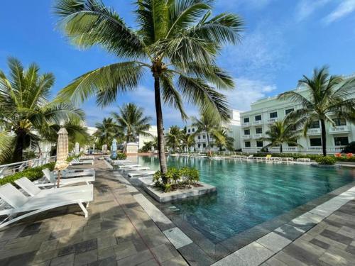 una piscina en un complejo con sillas blancas y palmeras en Minh Phu Quoc lodge beach swimming pool en Phu Quoc