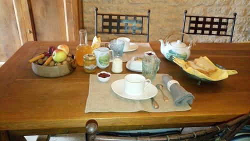 una mesa de madera cubierta con platos y tazones de comida en Le Clos Saint Georges, en Donnazac