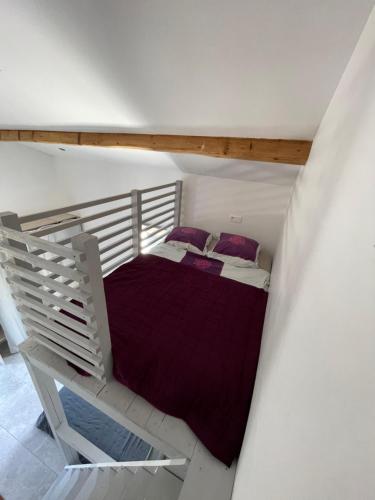 an attic room with a bed with purple pillows at Villa Pierre et Mer, maison 6 personnes a deux pas des plages in Hyères