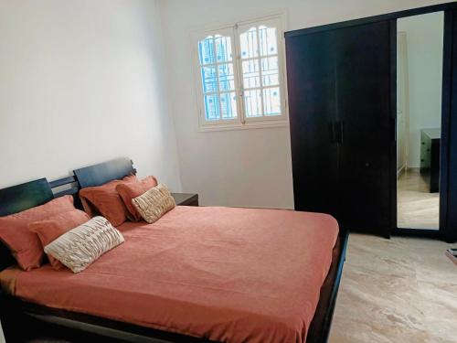 sypialnia z łóżkiem z pomarańczową pościelą i oknem w obiekcie VILLA AMEL w mieście Al Ḩārah al Kabīrah