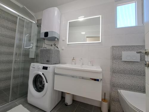 a bathroom with a washing machine and a sink at Holiday house SeaDream - 50 meters from the sea in Brodarica