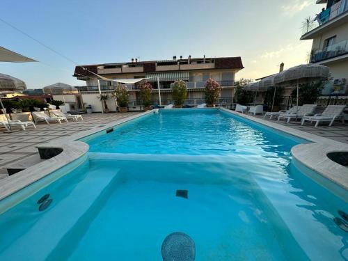 uma grande piscina azul com cadeiras e um edifício em Hotel Costa Verde em Pineto