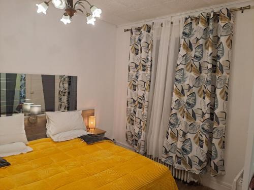 a bedroom with a bed with a yellow blanket at VILLULA in Gien