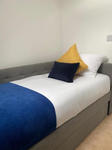 ein Bett mit blauen und weißen Kissen darauf in der Unterkunft Kingsway House - Spacious 4 Bed Home From Home in Derby in Derby