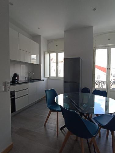 a kitchen with a glass table and blue chairs at FAMILY Apartamento I in Coimbra