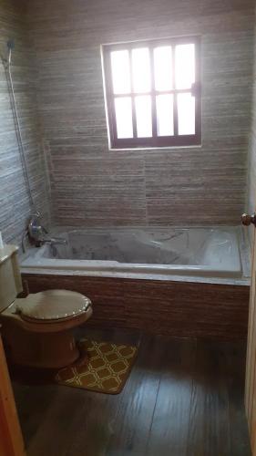 La salle de bains est pourvue de toilettes et d'une baignoire avec fenêtre. dans l'établissement Cabaña cruz verde, à Pinal de Amoles