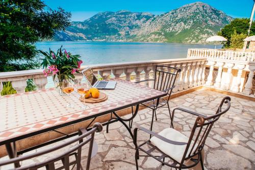 a table with a laptop on a balcony with a view of the water at Villa Chantal in Kotor