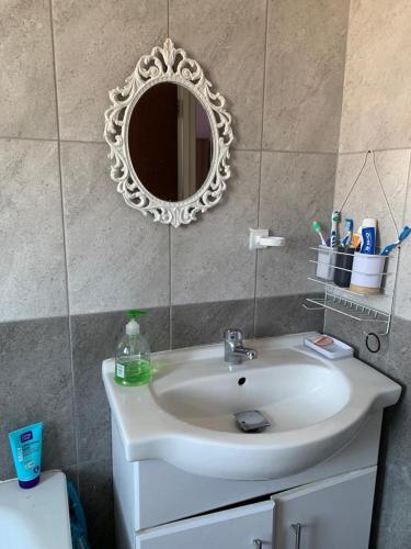 uma casa de banho com um lavatório branco e um espelho. em Your Perfect HomeStay em Ilford