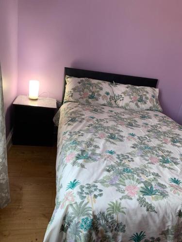 a bed with a floral comforter in a bedroom at Your Perfect HomeStay in Ilford