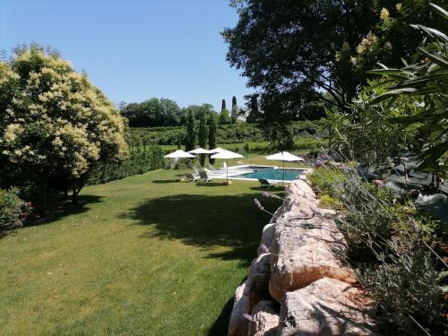 a garden with umbrellas and a stone wall at Relais Ca' Morenica in Valeggio sul Mincio