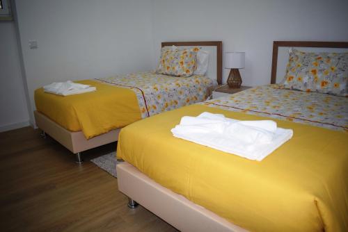 um quarto com 2 camas com lençóis amarelos em Conchada House 13 em Coimbra