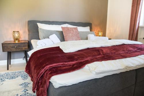 1 dormitorio con 1 cama grande con manta roja en UNiQE I Stilvolle 115qm I Terrasse I BBQ, en Feldafing