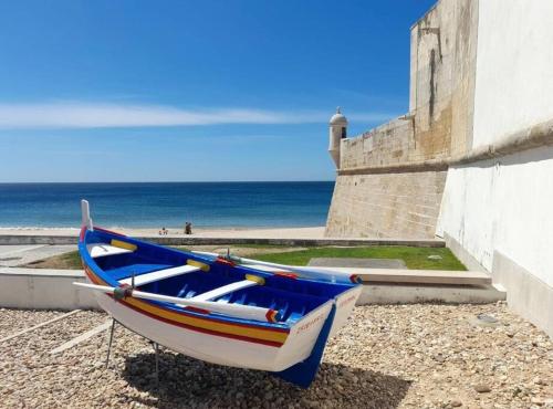 un barco sentado en la playa junto a un edificio en Casa da fortaleza en Sesimbra