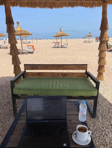 a laptop computer sitting on a bench on the beach at Cosy Apartment with sea view in Sidi Rahal