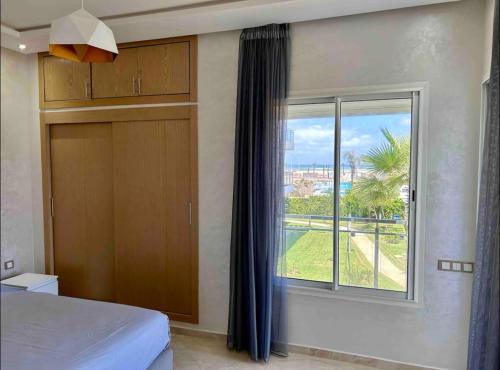 a bedroom with a bed and a large window at Cosy Apartment with sea view in Sidi Rahal