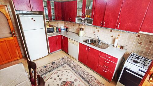 Il comprend une cuisine équipée de placards rouges et d'un réfrigérateur blanc. dans l'établissement Tepedeki Ev, à Akcaabat
