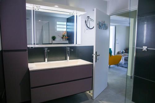 een badkamer met een wastafel en een spiegel bij LES NUITS GALANTES VILLA PETREA PISCINE PRIVÉE in Saint-François