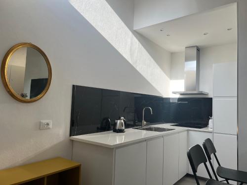 uma cozinha branca com um lavatório e um espelho em Casa Cielo Universitas em Bolonha