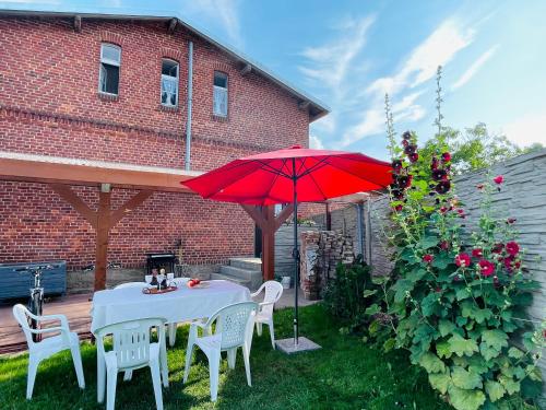 a table and chairs with a red umbrella in a yard at Apartamenty Cegiełka in Gąski