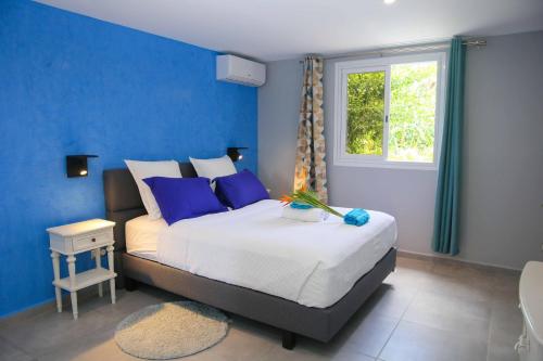 een slaapkamer met een bed met blauwe muren en een raam bij LES NUITS GALANTES VILLA PETREA PISCINE PRIVÉE in Saint-François