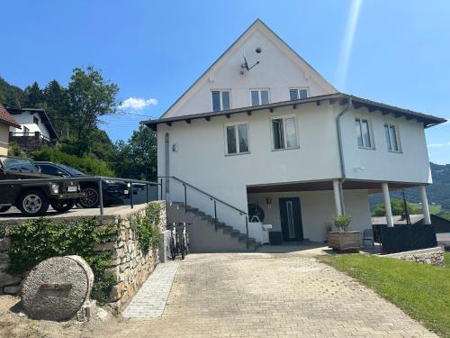 a white house with a car parked in a driveway at Panoramablick Scheifling in Lind bei Scheifling