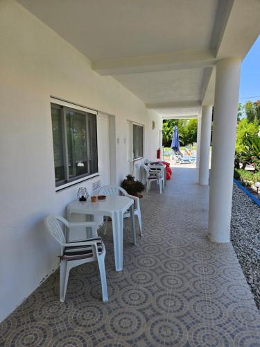 a porch with white chairs and a table and a window at Casa Zanzibar Hotel in Landeira