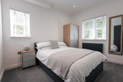 a white bedroom with a bed and a mirror at Harbour House in Plymouth