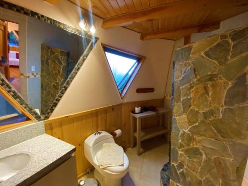 a bathroom with a toilet and a rock wall at Domo La Luz in Olmué
