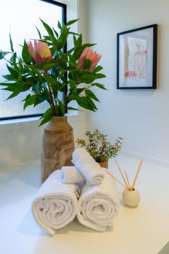 a bathroom counter with towels and a vase with flowers at Haven near Hagley Park, Hospital, Parakiore, Avon in Christchurch
