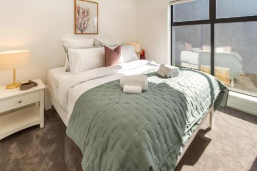 a bedroom with a large bed with two towels on it at Beautiful Gem by Hagley Park, Central City Chch in Christchurch