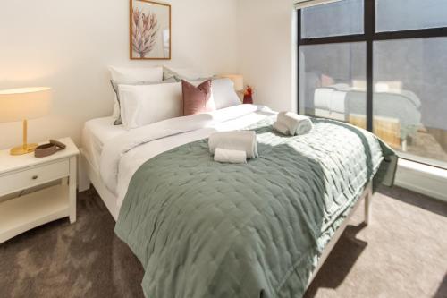 a bedroom with a large bed with two towels on it at Haven near Hagley Park, Hospital, Parakiore, Avon in Christchurch