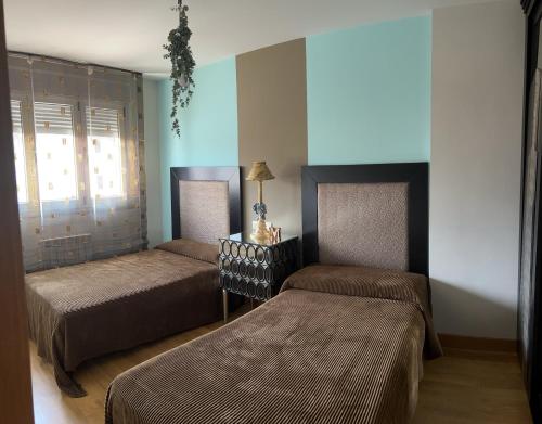 a bedroom with two beds and a lamp on a table at La Casa de Blanca in Candás