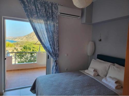 a bedroom with a bed and a large window at 180 Degree Sea View Apartment in Palaiochora