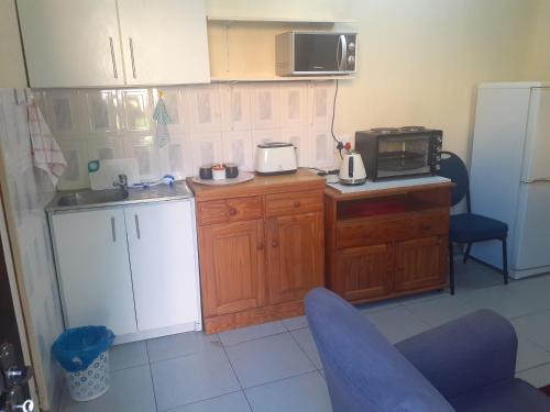 a kitchen with wooden cabinets and a microwave and a refrigerator at Carol Cottage Fun in Johannesburg