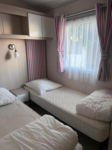 deux lits jumeaux dans une chambre avec fenêtre dans l'établissement Mobil home le Montourey, à Fréjus