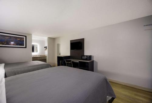 a hotel room with two beds and a desk at Quality Inn Tallahassee near University in Tallahassee