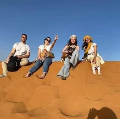 a group of people sitting on a rock in the desert at Bivouac Camel Trips in Merzouga