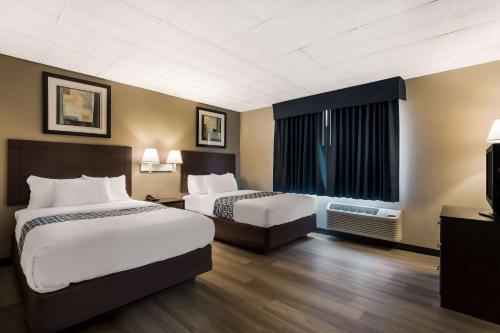 um quarto de hotel com duas camas e uma janela em Suburban Studios Millville em Millville