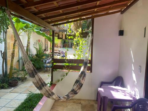 a hammock on a patio with a table and chairs at Pousada MYM JERI ate 3x in Jericoacoara