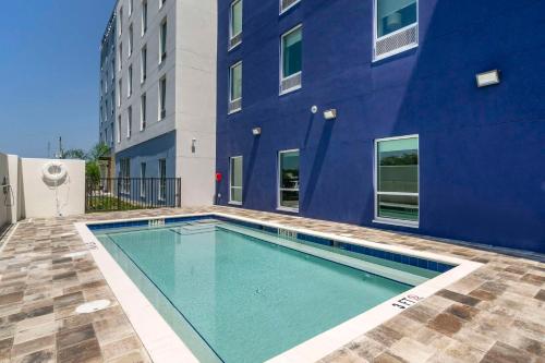 une piscine en face d'un bâtiment bleu dans l'établissement Comfort Inn & Suites New Port Richey Downtown District, à New Port Richey