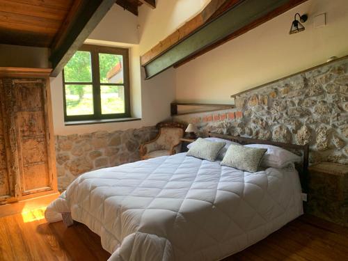 a bedroom with a large bed with a stone wall at La Fontanina de Mario in Villaviciosa