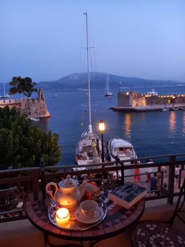 a table with a tea set on a balcony with boats at Casa da Sogno Elegant Studio in Nafpaktos