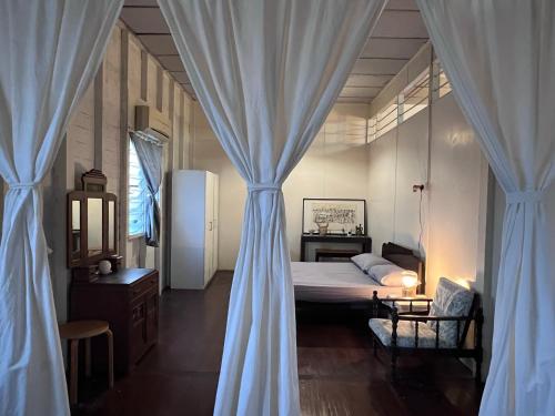 1 dormitorio con 1 cama con cortinas y mesa en 吉胆岛 潮汐民宿 Pulau Ketam Tide Homestay, en Bagan Teochew
